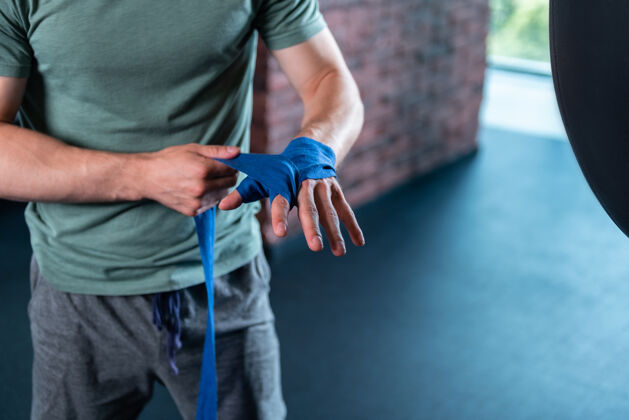 女性在健身房拳击英俊强壮的肌肉男使用专业的蓝色护腕在健身房拳击前健身房运动动作