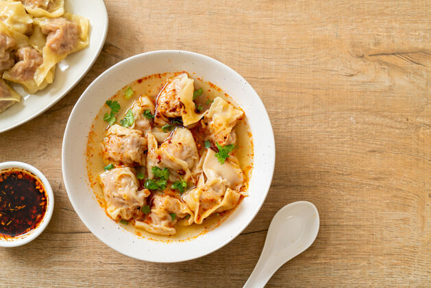 碗猪肉馄饨汤或猪肉饺子汤配烤辣椒-亚洲风味中国菜午餐饺子