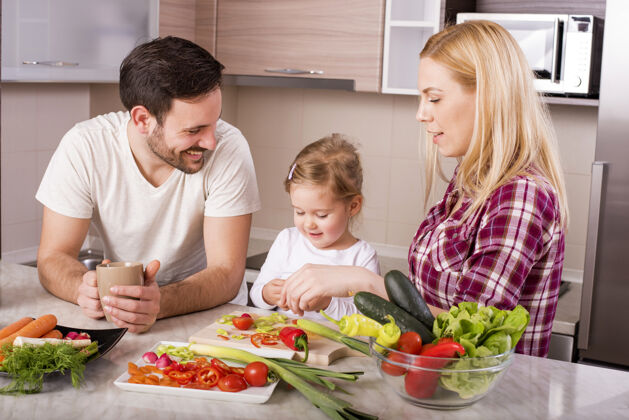 快乐快乐家庭在厨房柜台上用新鲜蔬菜做沙拉房子室内蔬菜