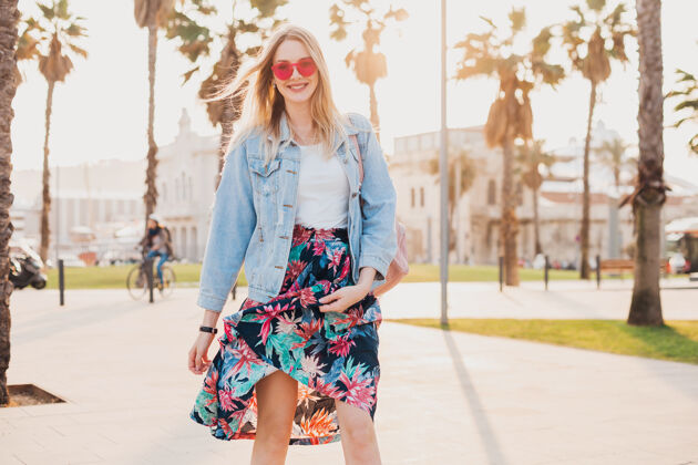 太阳镜美丽的微笑 调情 浪漫的女人走在城市街道时尚的印花裙和牛仔超大夹克穿着粉红色太阳镜衣服头发城市