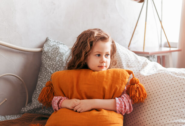 放松可爱的小女孩在儿童卧室的床上抱枕房子睡衣舒适