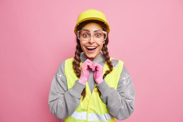 安全修缮概念积极的女机械师穿着工程建筑制服 在粉红色的墙壁上看起来很快乐工程和工业建筑穿着工作服的工人制服工作安全