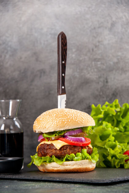 芝士汉堡特写镜头刀在美味的肉三明治和青椒在黑色托盘酱番茄干灰色表面奶酪胡椒粉西红柿