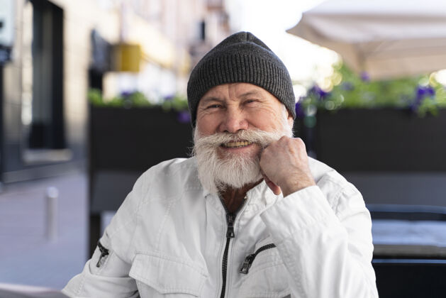 城市中景笑脸男人坐在露台上退休生活方式老年人