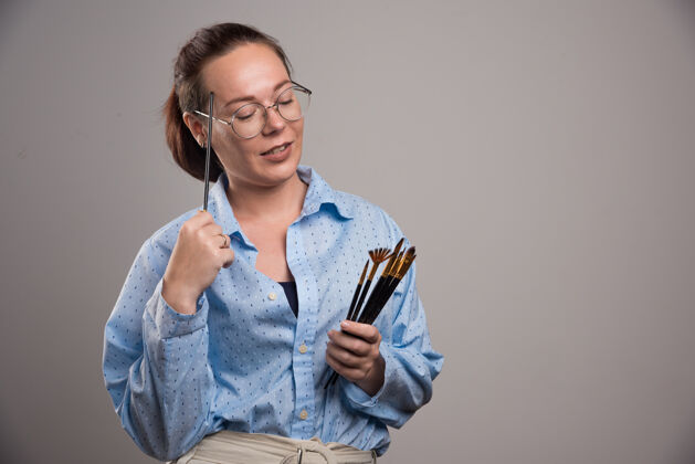 设备女艺术家拿着画笔在灰色高质量的照片画笔女性人类