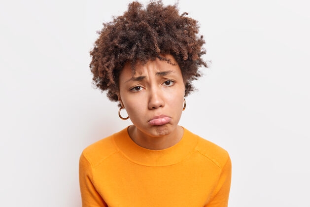 悲伤不满的特写镜头悲伤的非洲裔美国妇女被一个穿着橙色套头衫的人冒犯感到不满被隔离在白墙上感到遗憾和悲伤负面情绪姿势女孩钱包