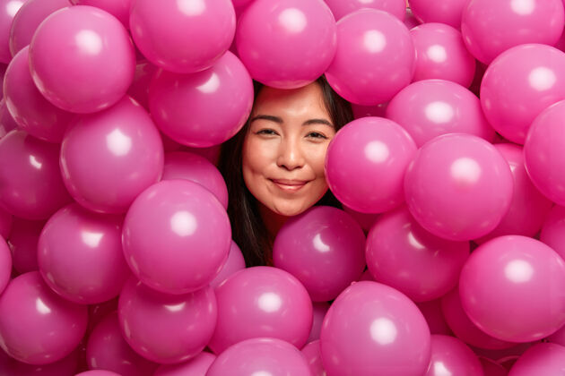 乐观女人在生日派对上被粉红色的充气气球团团围住了高兴节日姿势