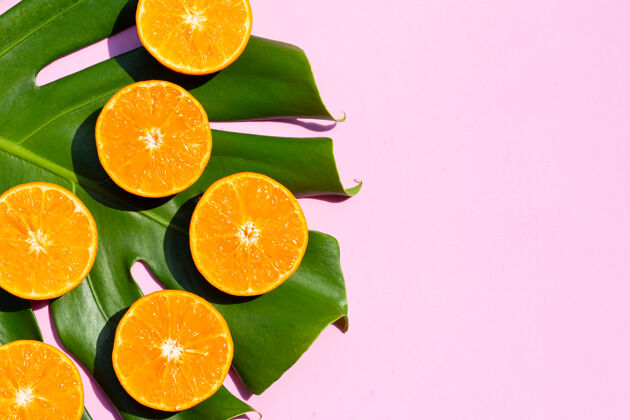 橙子高维生素c 多汁 营养丰富甜的新鲜的橙色水果 粉红色背景上有植物叶子配料多汁有机