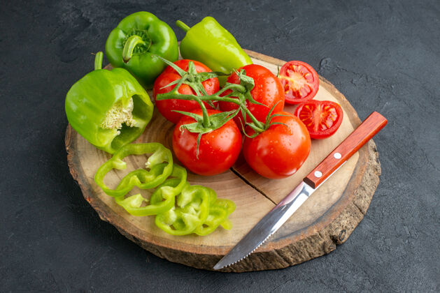 蔬菜全切切碎青椒和新鲜西红柿的特写镜头刀放在黑色表面的木质砧板上食物青椒健康