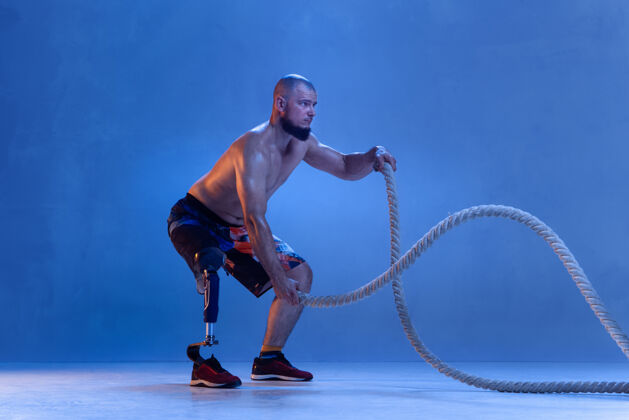 霓虹灯残疾运动员或截肢者被隔离在蓝色的墙上健美假肢运动