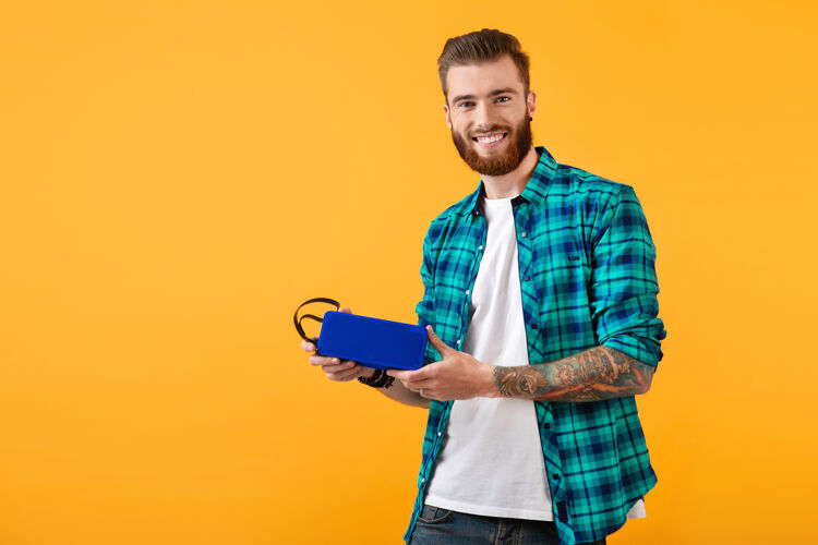 时尚时尚微笑的年轻人手持无线扬声器听音乐纹身科技欢乐