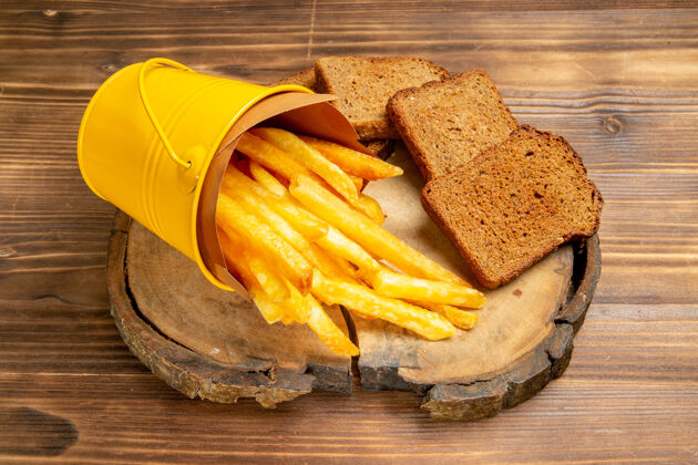 营养前视图炸薯条和黑面包面包放在棕色桌子上土豆快餐面包土豆正餐小吃