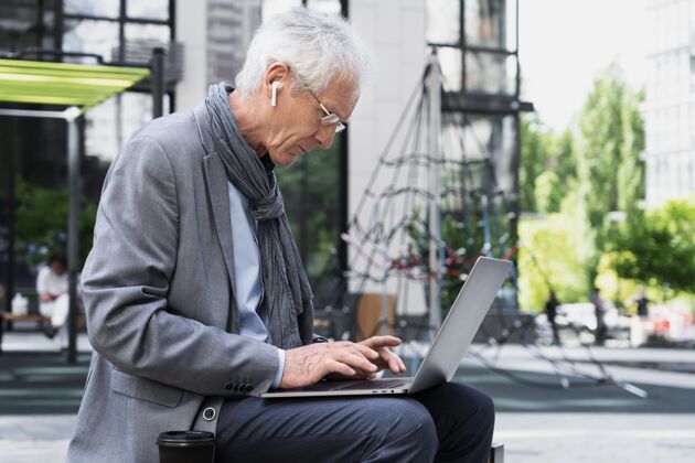 户外时尚的老男人在城市里使用笔记本电脑老年人男性水平