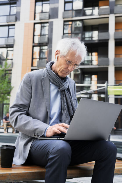 老年人时尚的老男人在城市里使用笔记本电脑男性成熟老年人