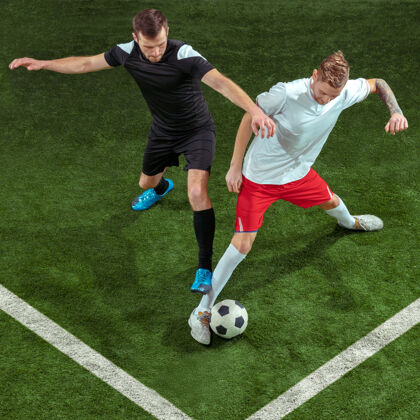 球员足球运动员在绿草背景上抢球职业男子足球运动员在体育场运动适合在运动中跳跃的男子 在比赛中跳跃 运动比赛冠军强壮