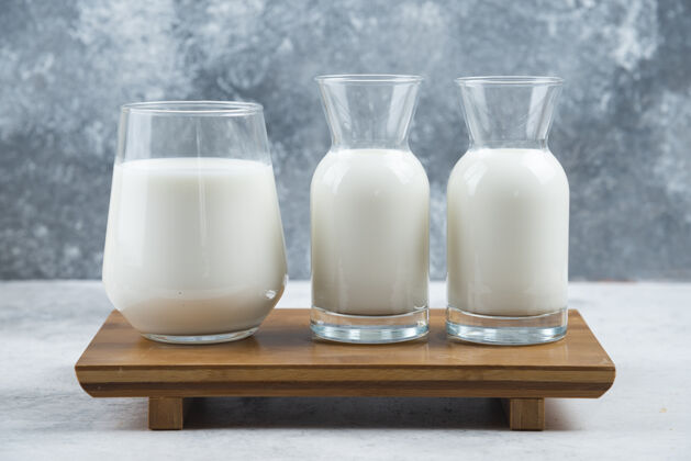 干净一杯牛奶和两杯牛奶放在一张小木桌上液体纯净奶制品