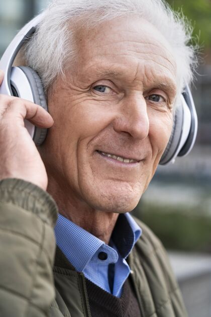 老年人笑眯眯的城里老人戴着耳机听音乐垂直老年人男性