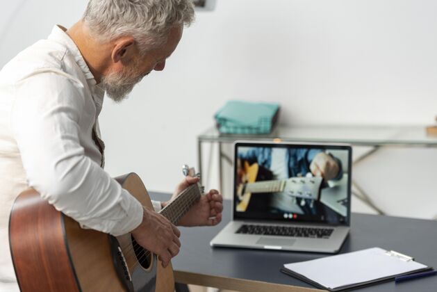 老年人在家学习吉他课笔记本电脑的高级男子养老金学习水平