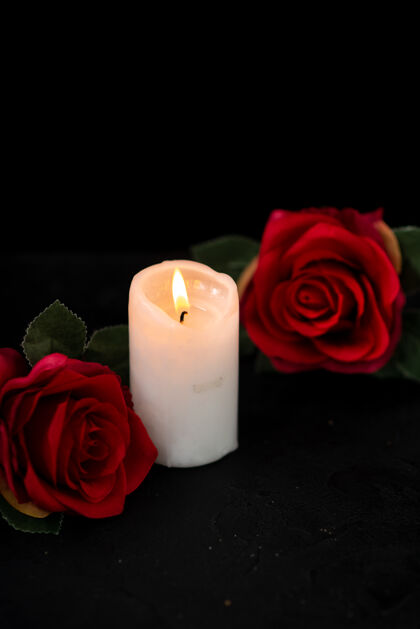 葬礼小墓穴的正面图 黑色上有蜡烛和红玫瑰死亡花瓣玫瑰