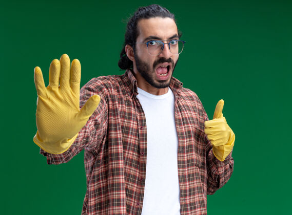 感觉年轻帅气的清洁工 穿着t恤 戴着手套 大拇指朝上 在绿色的墙上做着“停车”的手势衣服人严格