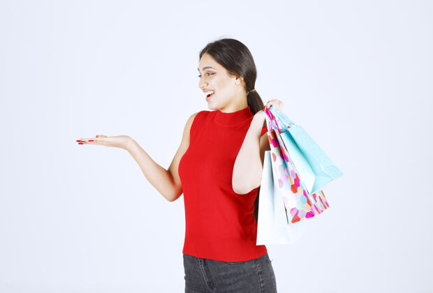 年轻人穿红衬衫的女孩肩后背着五颜六色的购物袋工人人姿势