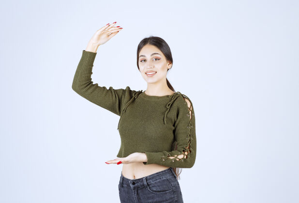 大一个年轻的微笑的女人用手做手势 显示出大大小小的标志尺寸手手势