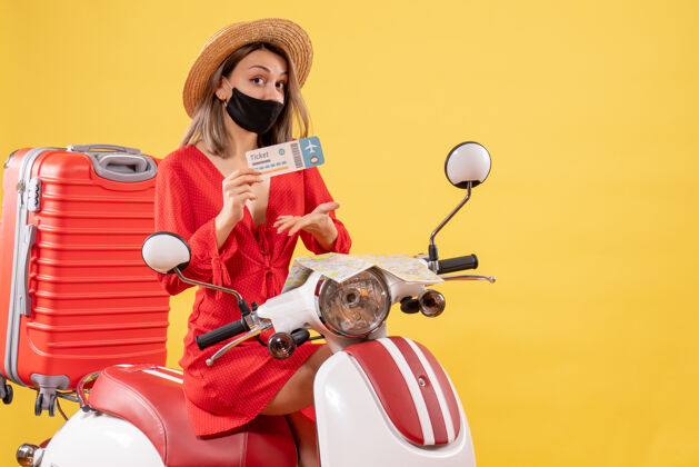 人正面图：一位身穿红色连衣裙 头戴巴拿马帽的年轻女士手持轻便摩托车度假持有行李