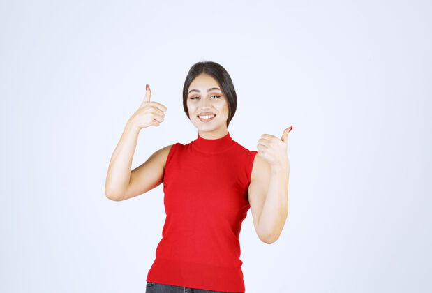 姿势穿红衬衫的女孩展示着快乐的手势幸运成功女性