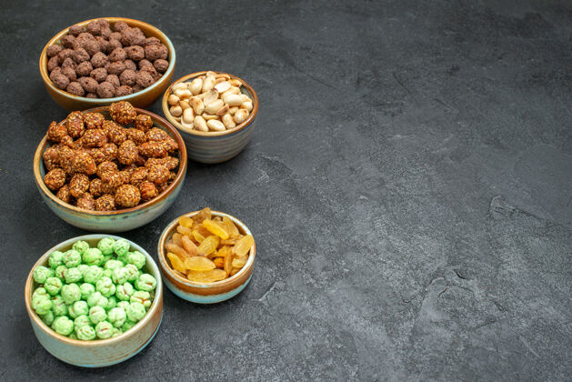 可食用的坚果前视不同的甜糖果与坚果和葡萄干的灰色空间碗香料晚餐