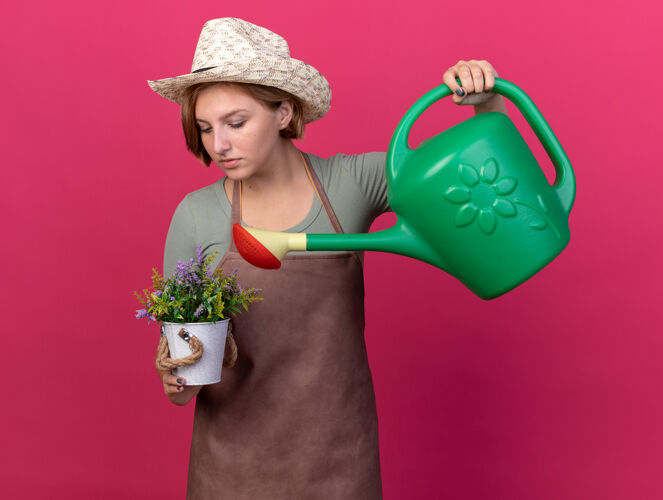 斯拉夫自信的年轻斯拉夫女园丁戴着园艺帽在花盆里用水壶浇花自信穿着浇水