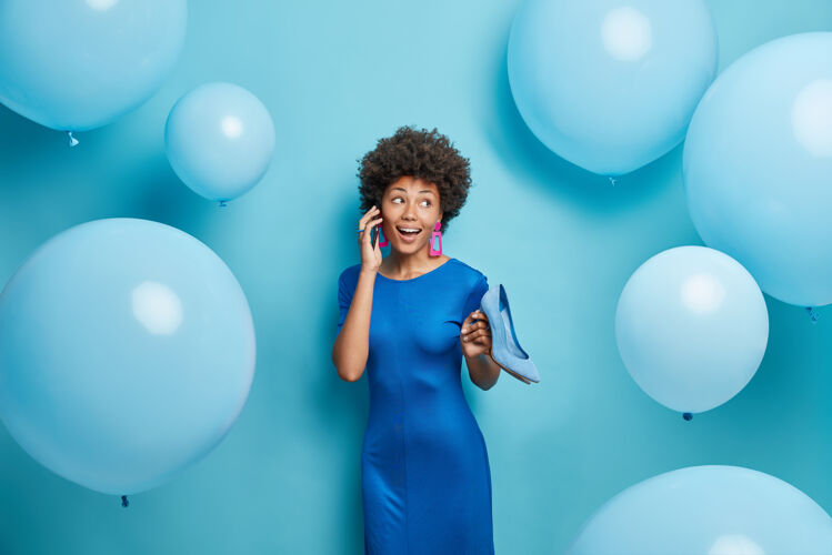 美国身着节日盛装 留着非洲头发的女人通过智能手机给某人打电话 安排蓝色的会议姿势时尚欣喜若狂活动