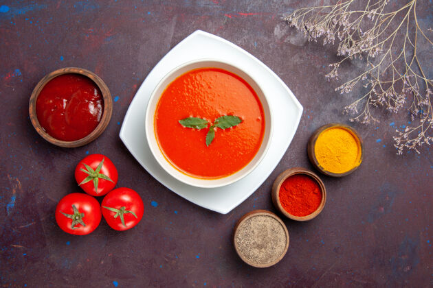 番茄俯瞰美味的番茄汤与调味料上的深色背景菜酱番茄色一餐汤碗盘子酱汁
