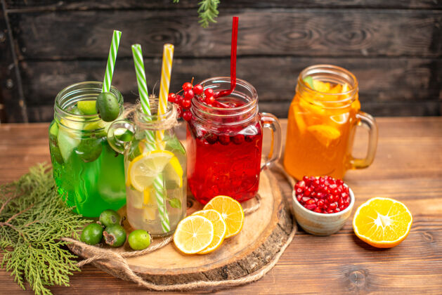 切俯瞰图有机新鲜果汁瓶与管和水果上的木制砧板上的棕色桌子玻璃果汁水果