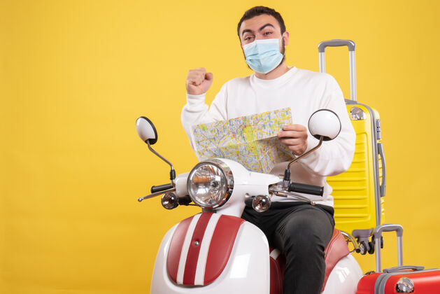 医疗旅行的概念与自豪的家伙在医疗面具坐在摩托车上 黄色的手提箱上 拿着黄色的地图手提箱男性车辆