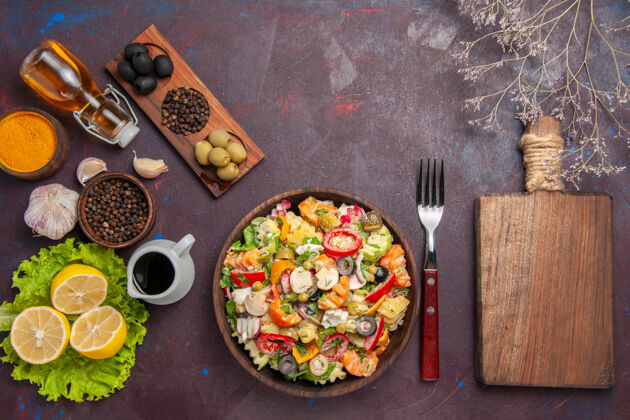顶部顶视图美味的蔬菜沙拉与新鲜柠檬片上的深色背景健康沙拉减肥餐零食饮食午餐观点