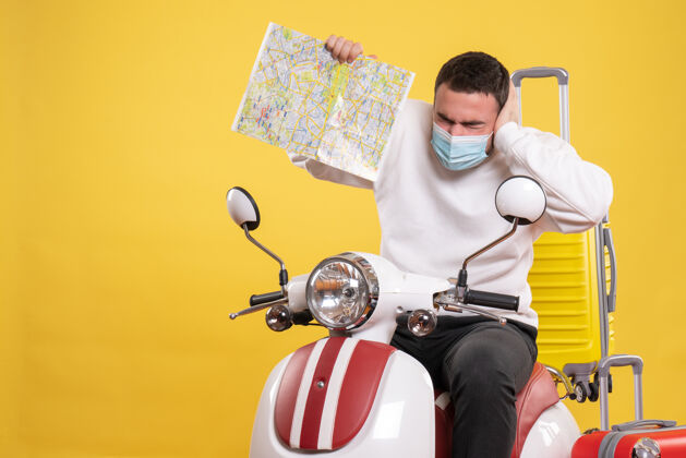 车辆旅行的概念 有问题的家伙在医疗面具坐在摩托车上 黄色手提箱上 并显示黄色地图摩托车手提箱面具