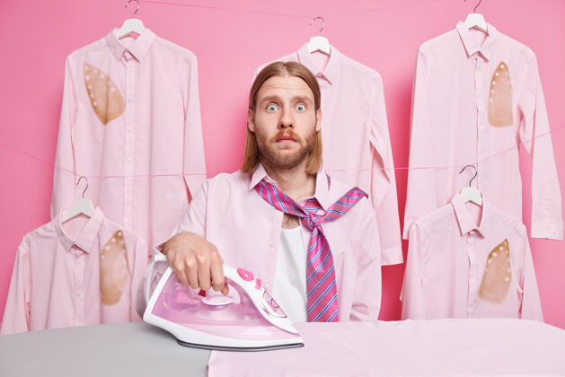 惊喜男人摸衣服用电熨斗穿衬衫和领带脖子上有很多工作要做粉红色的姿势男性家庭食宿