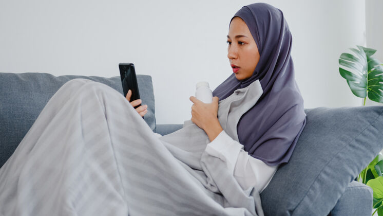 聊天年轻的女士戴着头巾 在家里客厅的沙发上通过电话视频通话与医生会诊或在线会诊社交诊断护理
