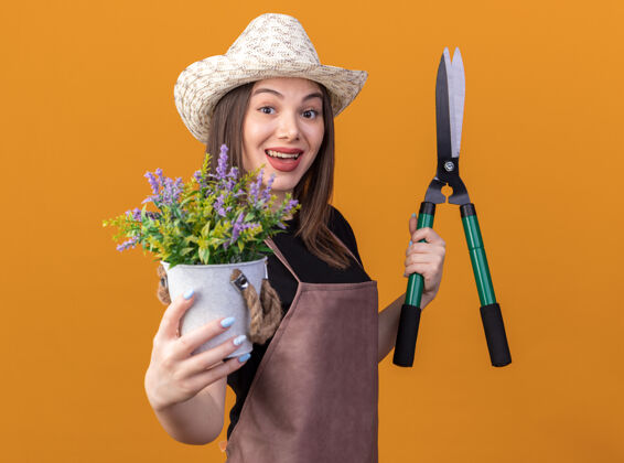 漂亮漂亮的白人女园丁戴着园艺帽手持园艺剪刀和花盆花园橘子女
