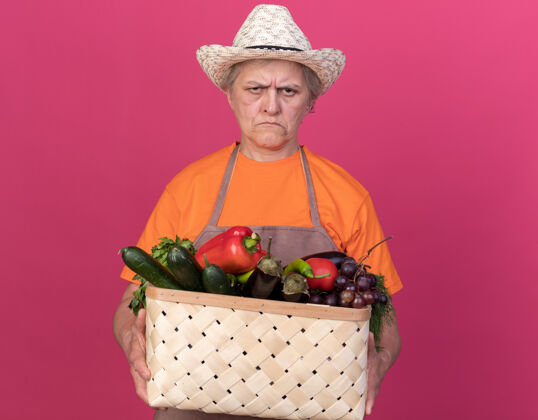 抱未出租的上了年纪的女园丁戴着园艺帽拿着菜篮子篮子园艺花园