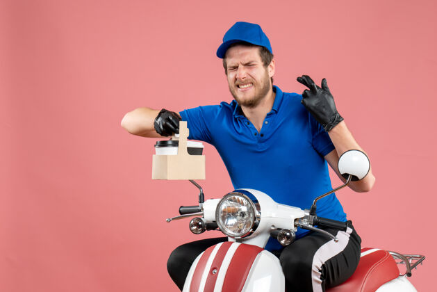 颜色正面图身穿蓝色制服的男快递员拿着咖啡在粉红色的工作快餐店送货自行车工人彩色工作男信使男人制服