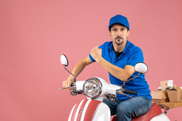 运动员前视图自豪的信使家伙戴着帽子坐在粉彩桃背景踏板车背景摩托车粉彩