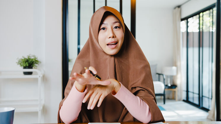 团队穆斯林女士戴着头巾用笔记本电脑在客厅远程工作时 在视频电话会议上和同事谈论计划穆斯林女性头巾