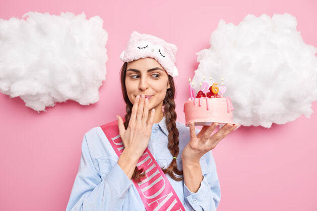 充气女人带着诱惑看着美味的蛋糕 嘴里等着客人 生日派对上戴着睡眠面具 衬衫上隔离着粉色蛋糕活动罗西