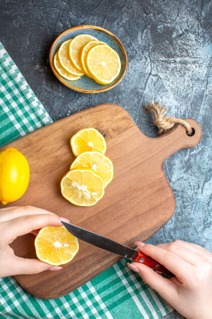 葡萄柚一只手在深色背景的木制砧板上切碎新鲜柠檬的垂直视图果汁板深色
