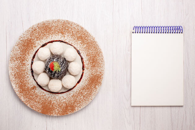视图俯瞰美味的椰子糖和巧克力蛋糕放在白色的桌子上蛋糕饼干甜甜的糖果饼干蛋糕碗食物
