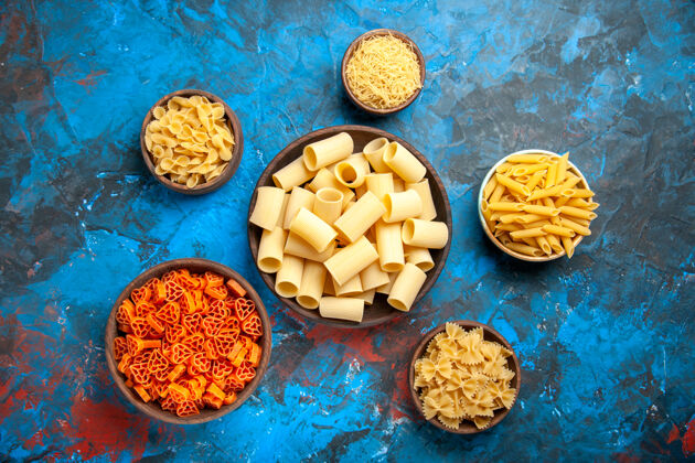 可食坚果蓝色背景上不同大小的锅中的意大利面晚餐准备俯视图食物美味一餐