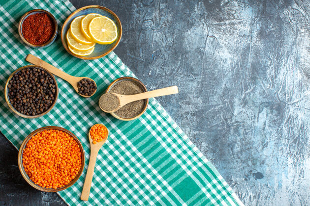 晚餐晚餐背景俯视图 不同香料黄色豌豆放在黑色桌子右侧的绿色条状毛巾上食物背景木勺