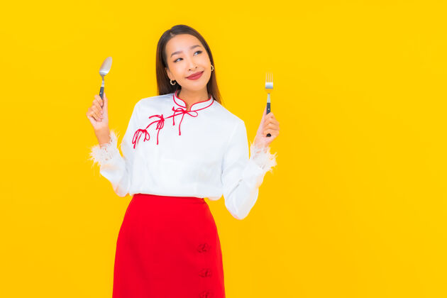 成人画一个年轻漂亮的亚洲女人 用黄色的勺子和叉子年轻休闲女人