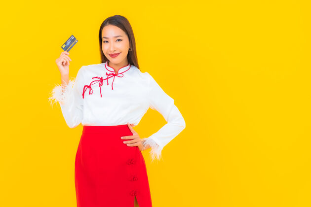消费者肖像美丽的亚洲年轻女子与信用卡网上购物黄色休闲金融购买